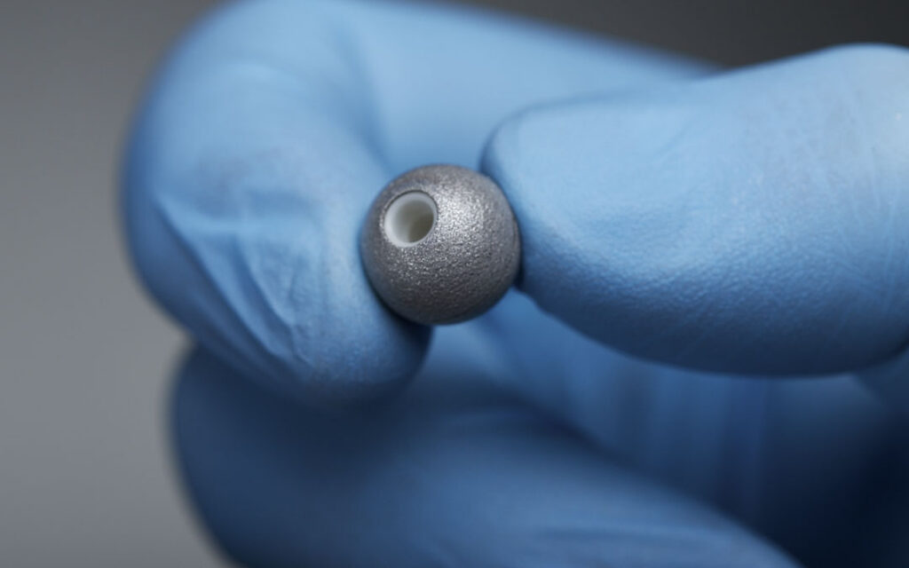 NDI Passive Sphere marker held between gloved fingers.