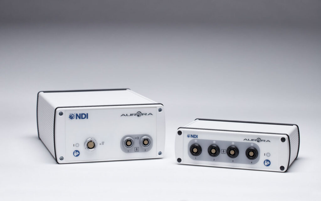 Two Aurora electromagnetic tracking system units shown side by side, displaying the front panels with NDI and Aurora branding and tool interface connector ports.