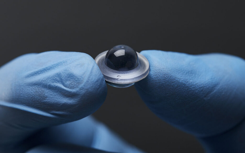 Polaris Radix Lens marker held between gloved fingers.