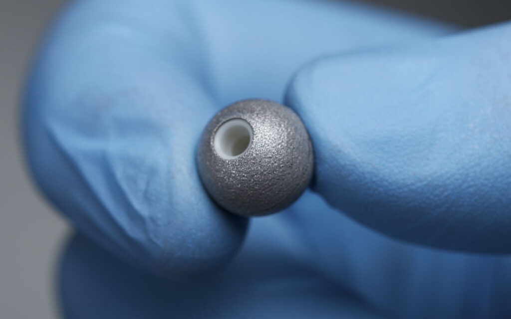 NDI Passive Sphere marker held between gloved fingers.