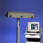 The Polaris P3 optical tracking system mounted on a stand next to a computer workstation displaying tracking data. Released in 1997.