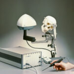 The Optotrak Certus optical measurement system positioned next to a model skull, with a handheld probe held over the skull during a research demonstration. Released in 2003.