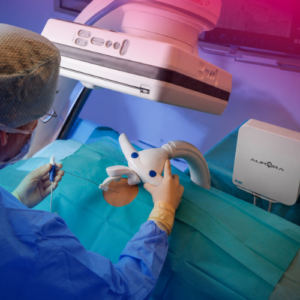 Gloved clinician positioning an NDI Aurora electromagnetic field generator and a tracked instrument over a draped surface, with the Aurora system unit on a stand nearby.