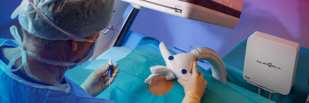Aurora electromagnetic tracking field generator beside a robotic needle placement setup with a tracked needle and patient reference
